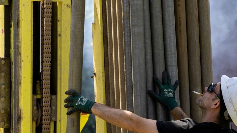 A Dandelion Energy employee inserts a drill extension while putting...