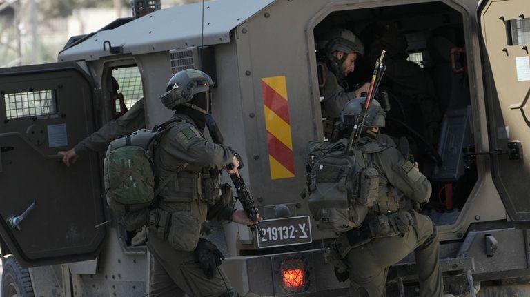 Members of Israeli forces prepare to enter in an armoured...