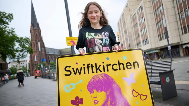 Schoolgirl Aleshanee Westhoff shows a "Swiftkirchen" town sign in honor...