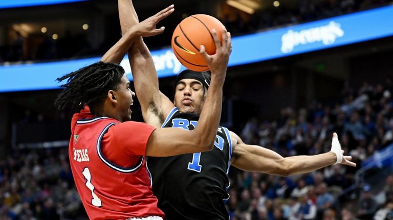 Fresno State guard Isaac Taveres, left, goes against BYU guard...