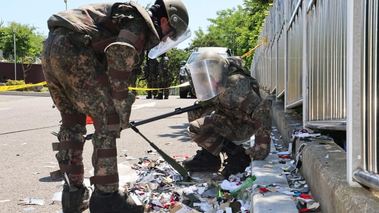South Korean soldiers wearing protective gears check the trash from...