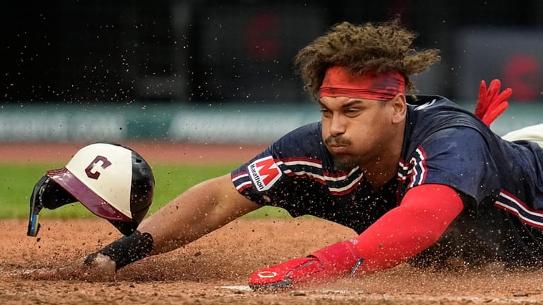 Cleveland Guardians' Josh Naylor slides head first into first base...