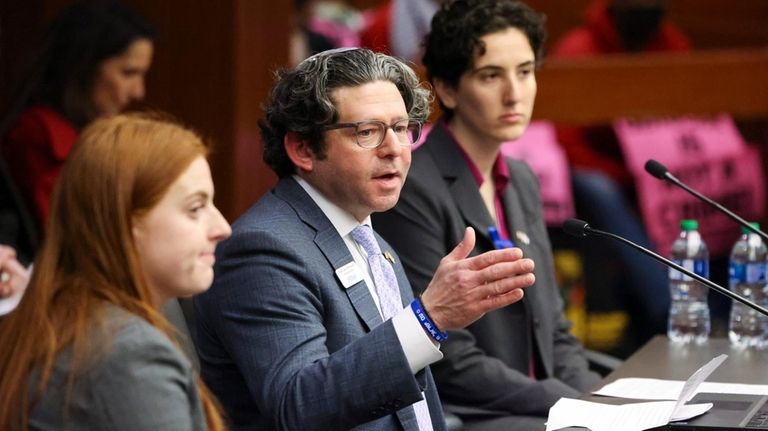 Rabbi Larry Sernovitz, with two local college students, speaks in...