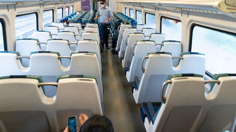 A Long Island Rail Road conductor checks tickets on a...