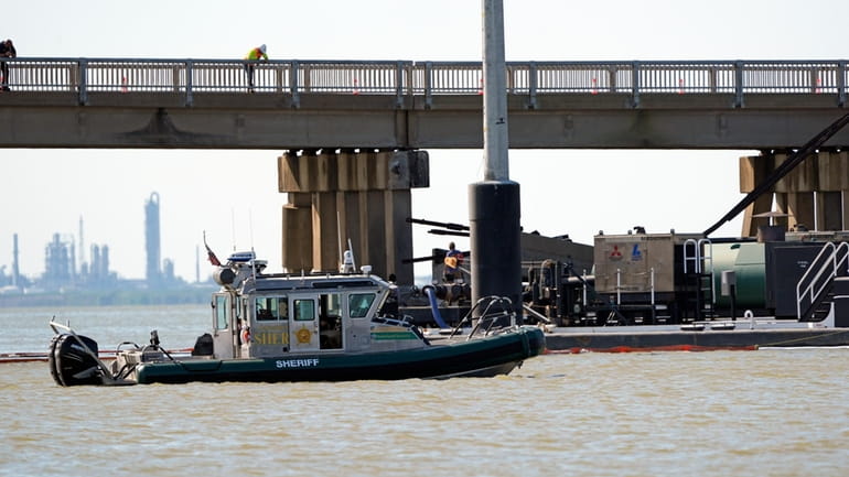 Officials patrol the waters at the site where a bardge...