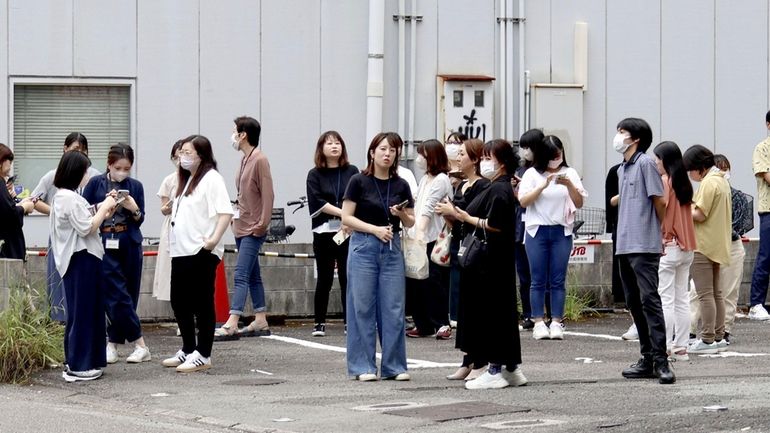 People take shelter outside building following an earthquake in Miyazaki,...