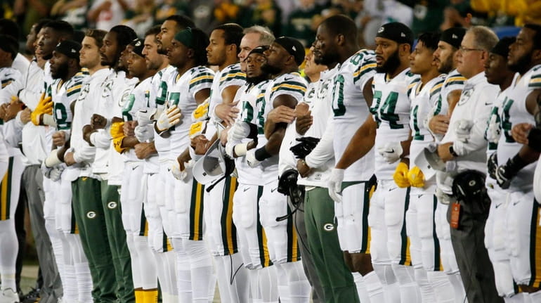 Green Bay Packers link arms during the national anthem on...