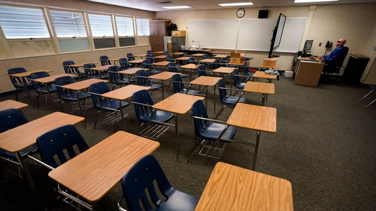 Math teacher Doug Walters sits among empty desks as he...