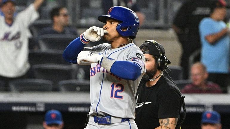 The Mets’ Francisco Lindor reacts as he scores on his...