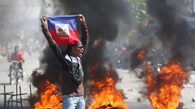A demonstrator holds up an Haitian flag during protests demanding...