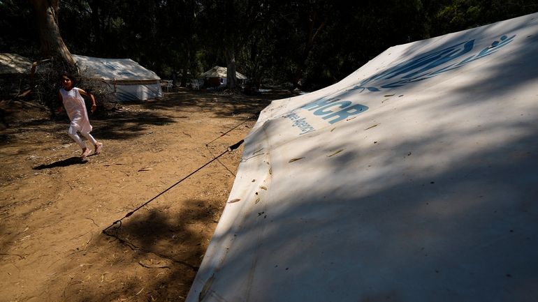 A girl runs next to the tents at a camp...