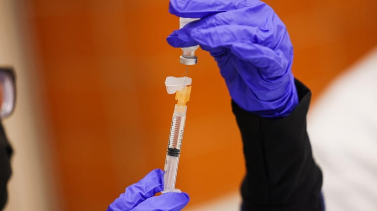 A Pfizer-BioNTech COVID-19 vaccine booster shot is prepped to be administered...