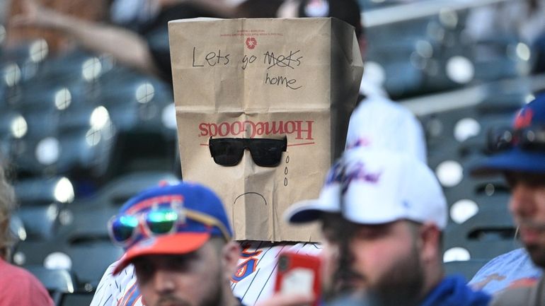 A New York Mets fan sits in the stands with...