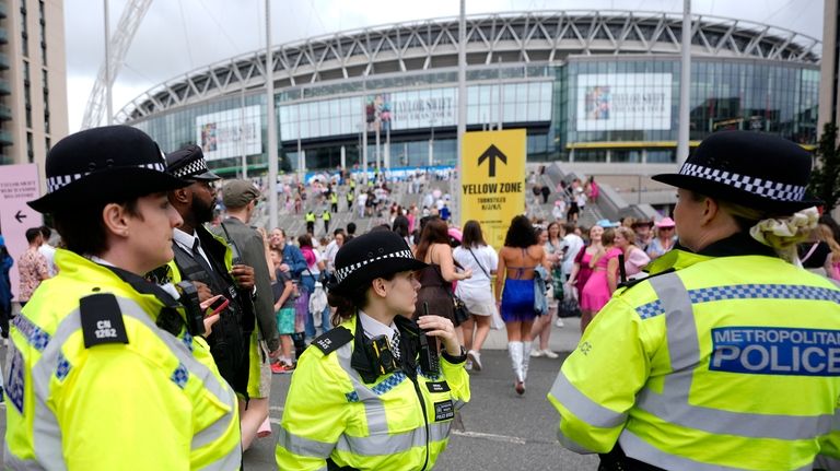 Police officers watch the arrival of Taylor Swift fans at...