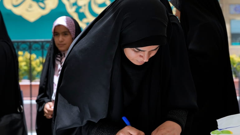 A woman fills out her ballot during the Iranian presidential...