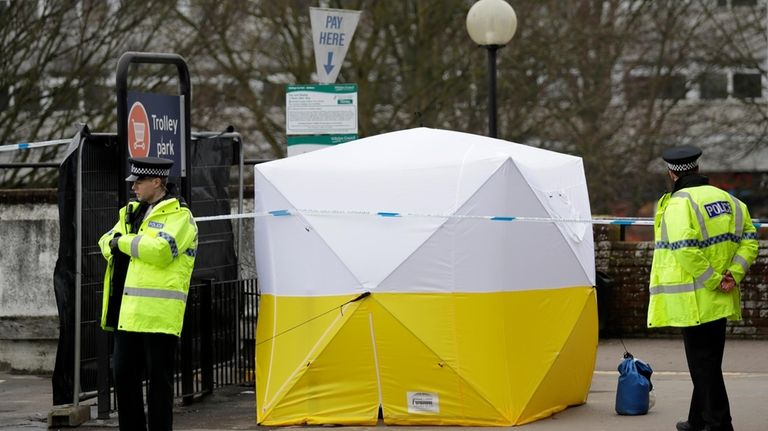 Police officers guard a supermarket parking facility near where former...