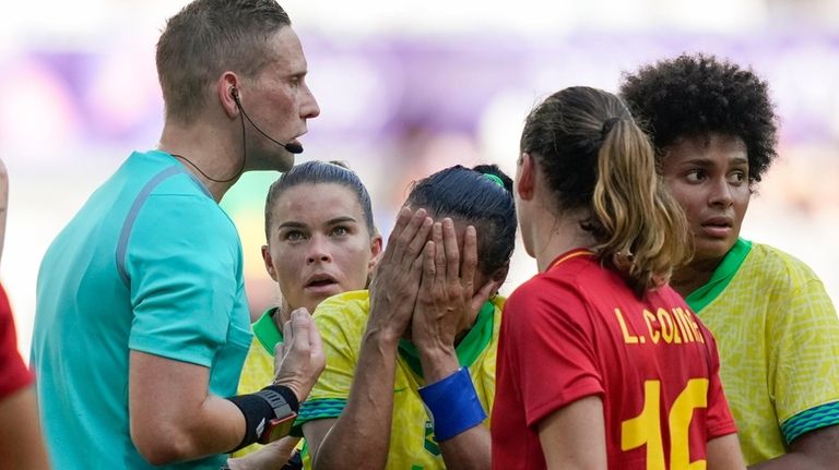 Brazil's Marta, center, reacts after receiving a red card from...