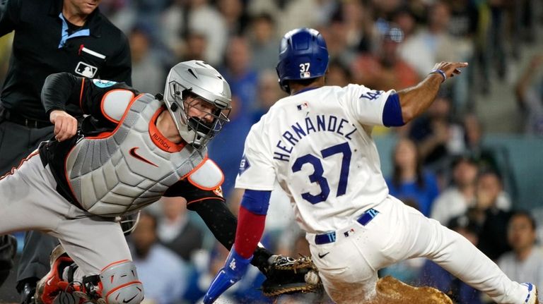 Los Angeles Dodgers' Teoscar Hernández, right, is tagged out by...