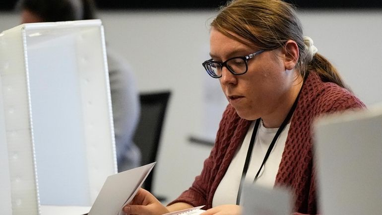 Elections assistant Mikayla Riley works in the processing center during...