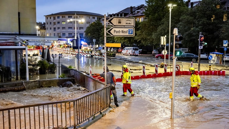 Firefighters look on as the Morges river overflows a road...