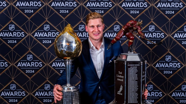 Colorado Avalanche forward Nathan MacKinnon stands with his trophies as...