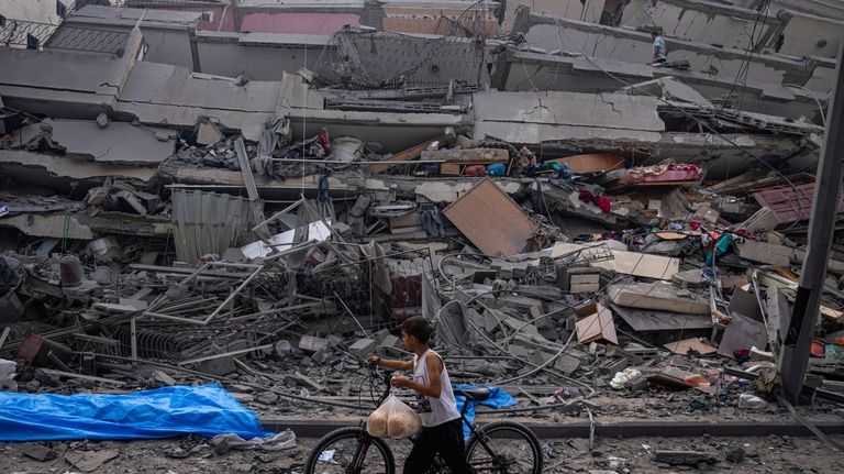 Palestinians kid walks by the rubble of a building after...