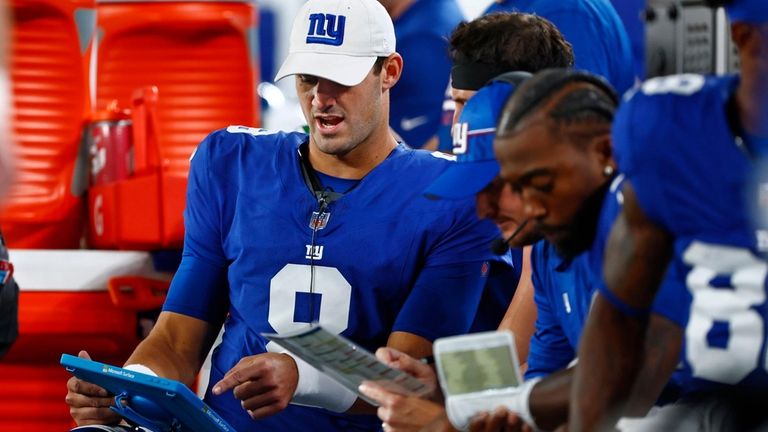 Giants quarterback Daniel Jones watches a play on a tablet...