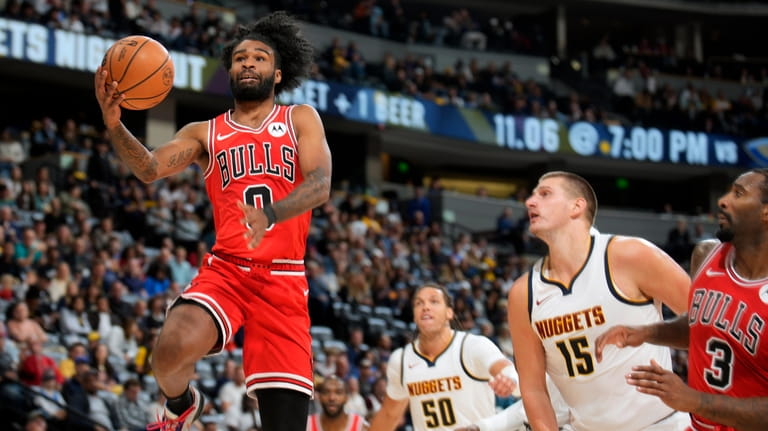 Chicago Bulls guard Coby White, left, drives to the rim...
