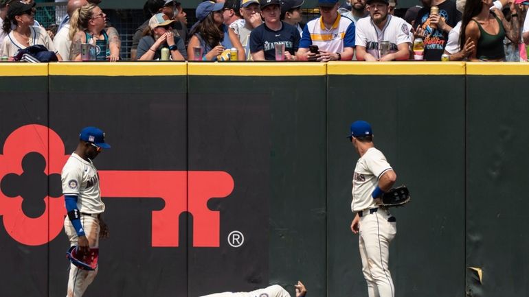 Seattle Mariners Julio Rodriguez, center, lies on the ground between...