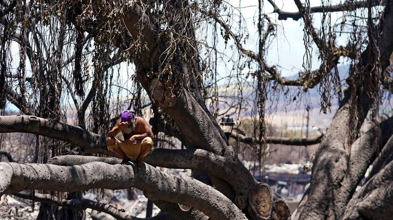 A man reacts as he sits on the Lahaina historic...