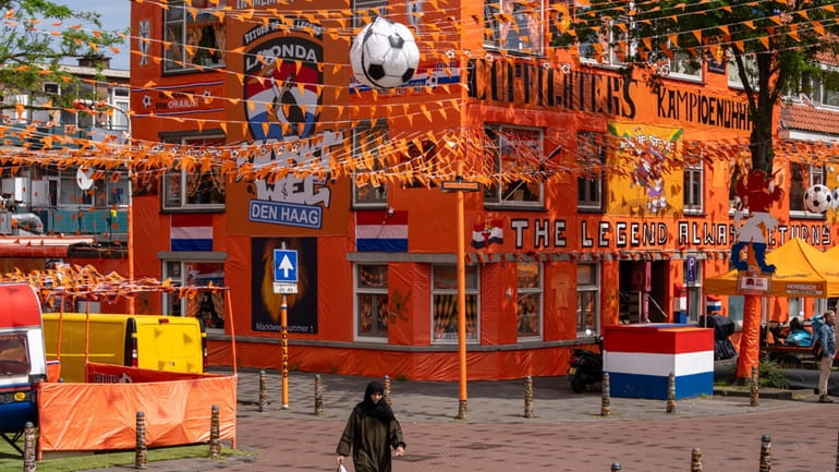 A women walks past inflatable soccer balls, orange tarp, orange...