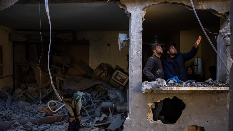 Palestinians look at the destruction after an Israeli strike in...