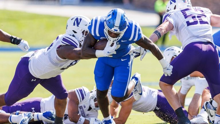 Duke's Jordan Waters, center, carries the ball between Northwestern's Najee...