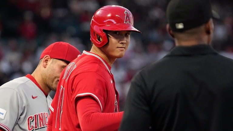 Los Angeles Angels' Shohei Ohtani, center, acknowledges first base umpire...