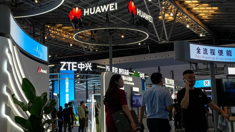 Visitors tour the Huawei and ZTE exhibition booths during the...