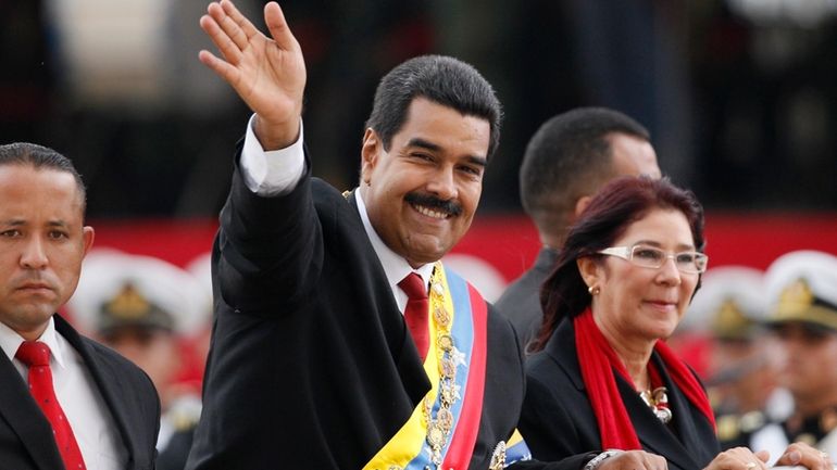 Venezuela's President Nicolas Maduro waves from a vehicle next to...