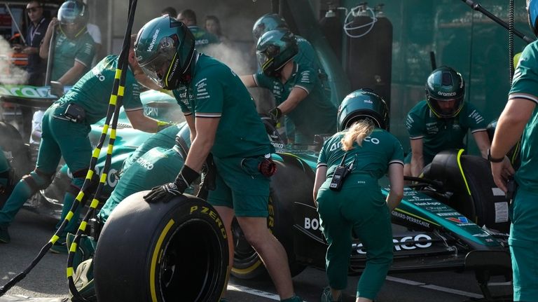 Technicians work on the car of Aston Martin driver Lance...