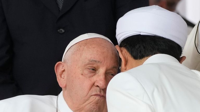 Pope Francis kisses with the Grand Imam Nasaruddin Umar, right,...