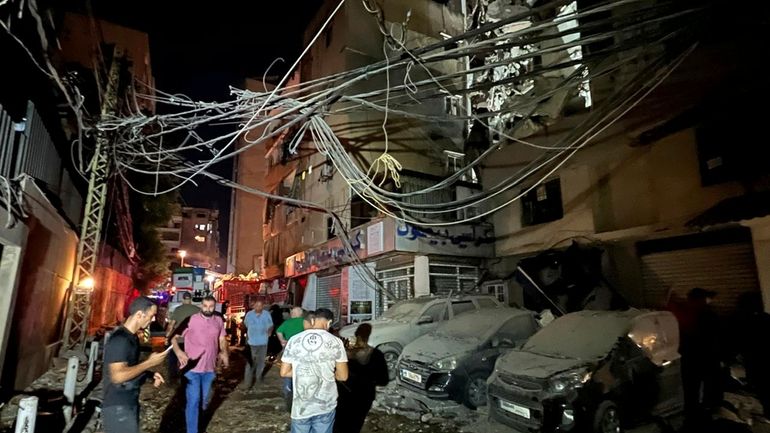 People gather near a destroyed building that was hit by...