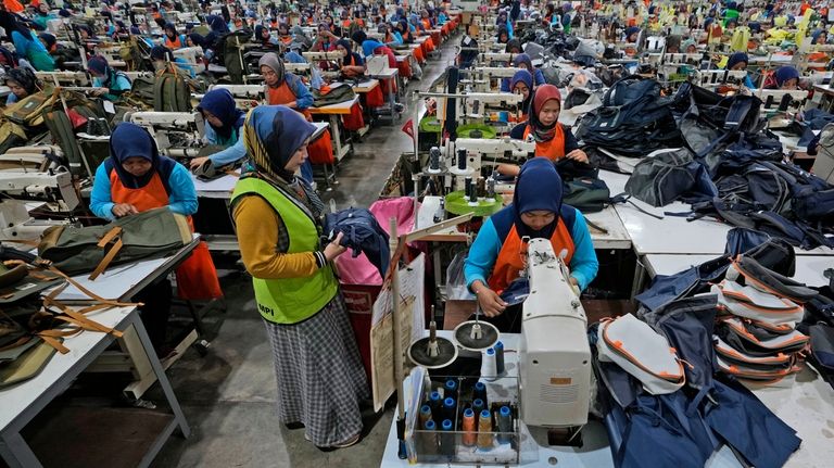 Workers sit in their stations at factory belonging to PT...