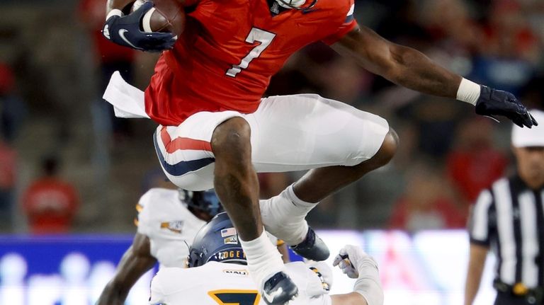 Arizona running back Quali Conley (7) hurdles over Northern Arizona...