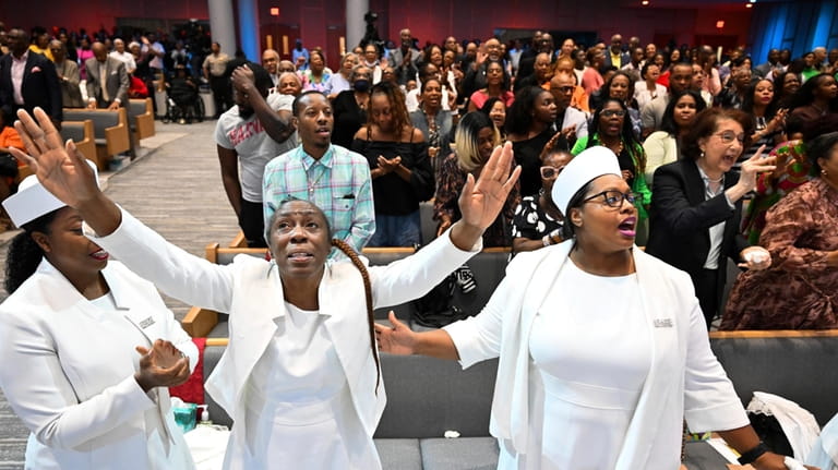 Members of the congregation at Kingdom Fellowship AME Church raise...