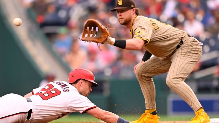 Washington Nationals' Lane Thomas dives back to first base as...