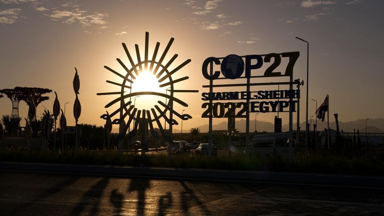 The sun sets behind the COP27 logo outside the venue...