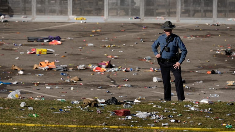 A law enforcement officer stands amid debris as he looks...
