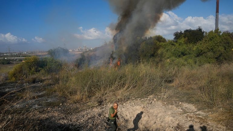 A police officer inspects the area around a fire after...