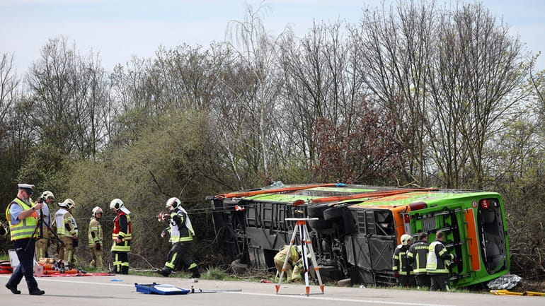 A coach lies overturned on its side at the scene...