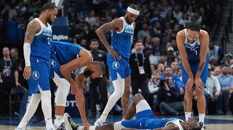 Minnesota Timberwolves guard Anthony Edwards, bottom, lies on the court...