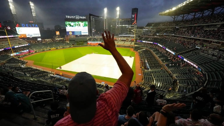A fan dances in the rain before a rain-delayed baseball...