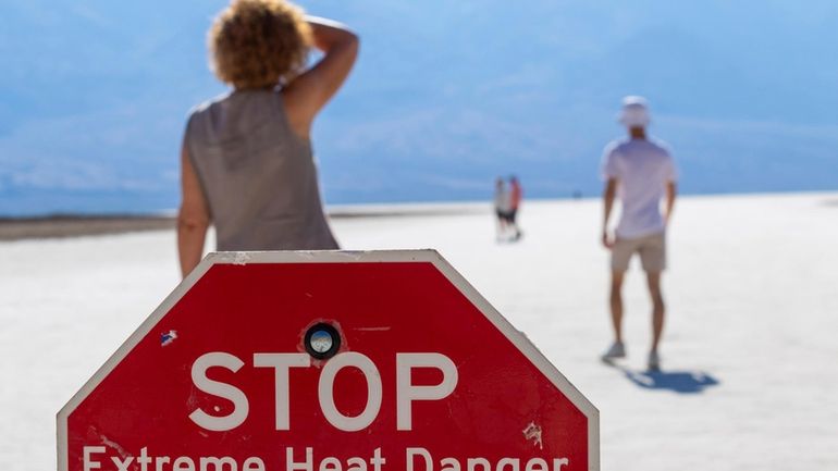 A person wipes sweat from their brow at Badwater Basin...